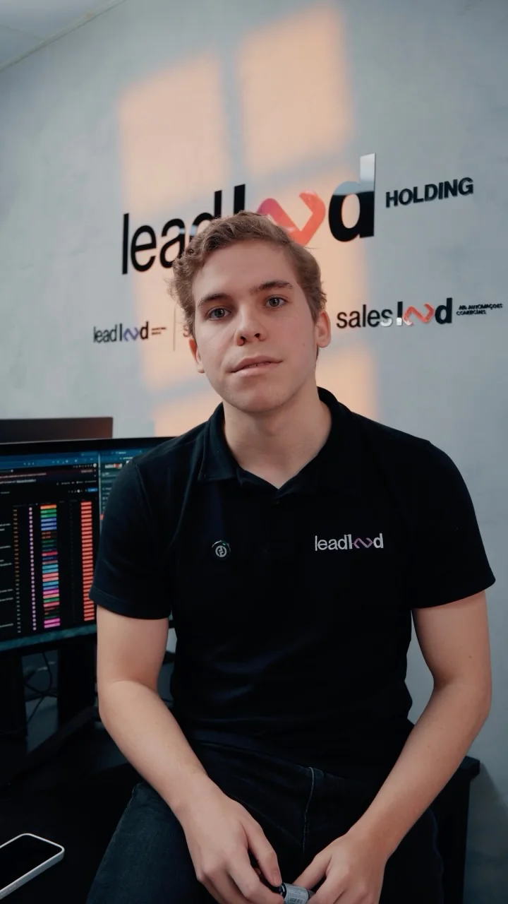 Felipe Freitas sentado na frente da parede do escritório, com a logo da Lead Land Holding e as marcas da holding